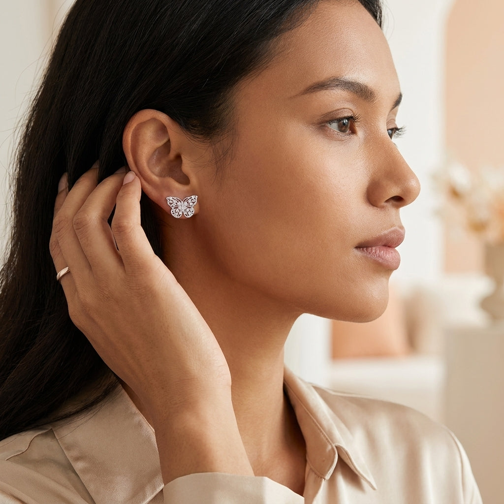 Woman touching a silver butterfly moissanite stud earring