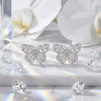 Butterfly moissanite stud earrings displayed with white orchids and crystal accents