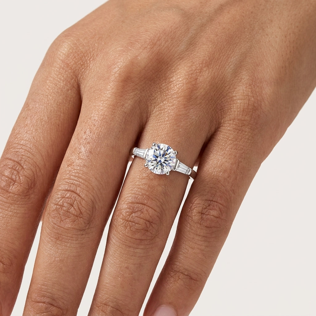 Close-up of a round moissanite engagement ring with tapered side stones