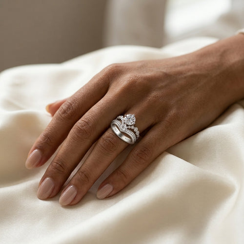 3 CT crown moissanite engagement ring worn on a hand resting on cream satin