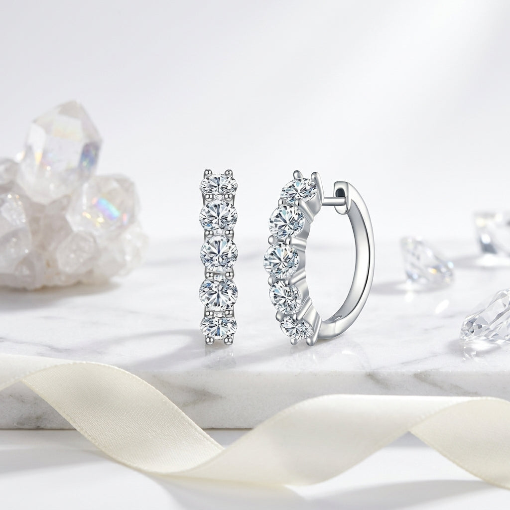 Five-stone moissanite hoop earrings displayed with crystals and cream ribbon
