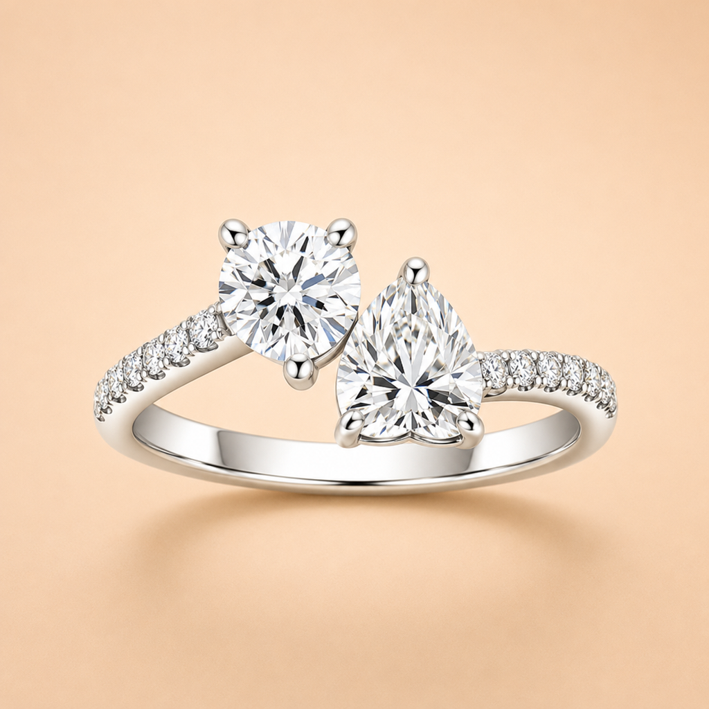 Two-stone moissanite engagement ring with round and pear-cut stones and pavé shoulders