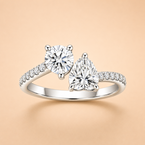 Two-stone moissanite engagement ring with round and pear-cut stones and pavé shoulders