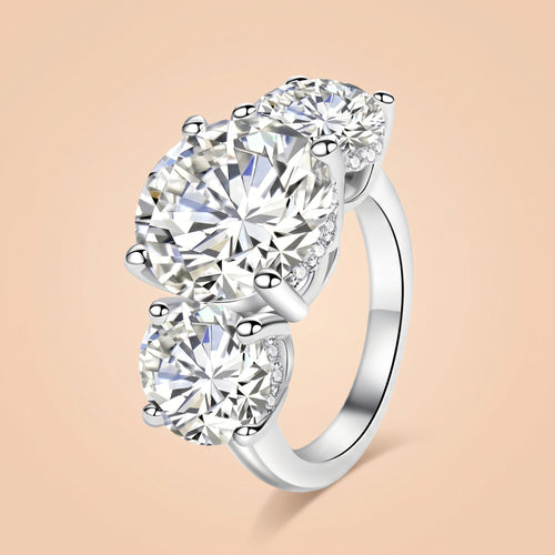 11 CTTW round-cut three-stone moissanite engagement ring in sterling silver on a peach background