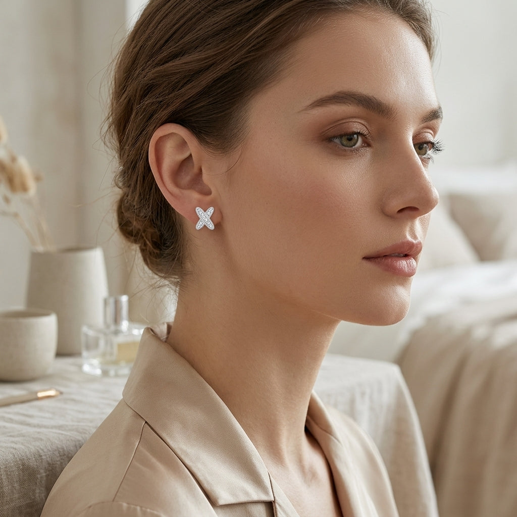 Woman wearing a silver moissanite cross stud earring with a beige blouse
