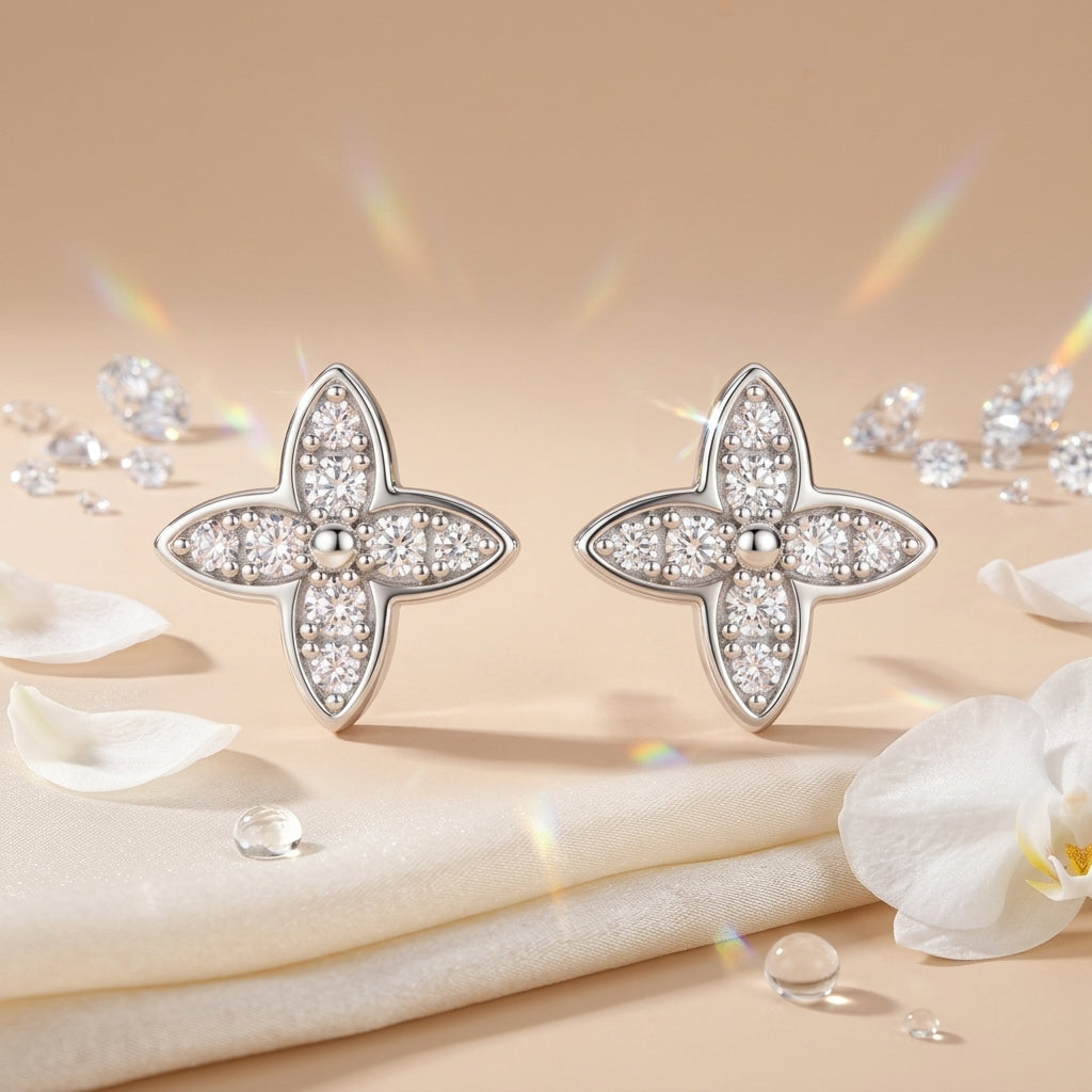 Four-leaf moissanite stud earrings displayed with white flowers and sparkling crystals