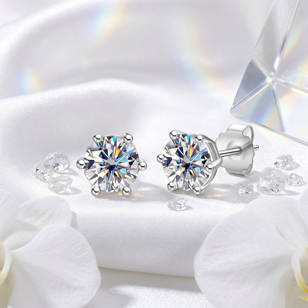 Round moissanite stud earrings displayed on white satin with crystal accents