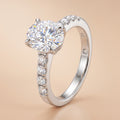 3 CT oval-cut moissanite engagement ring with pavé sterling silver band on a beige background.