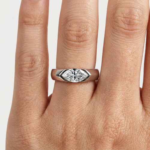 Marquise moissanite ring displayed on marble with crystals and a white flower petal