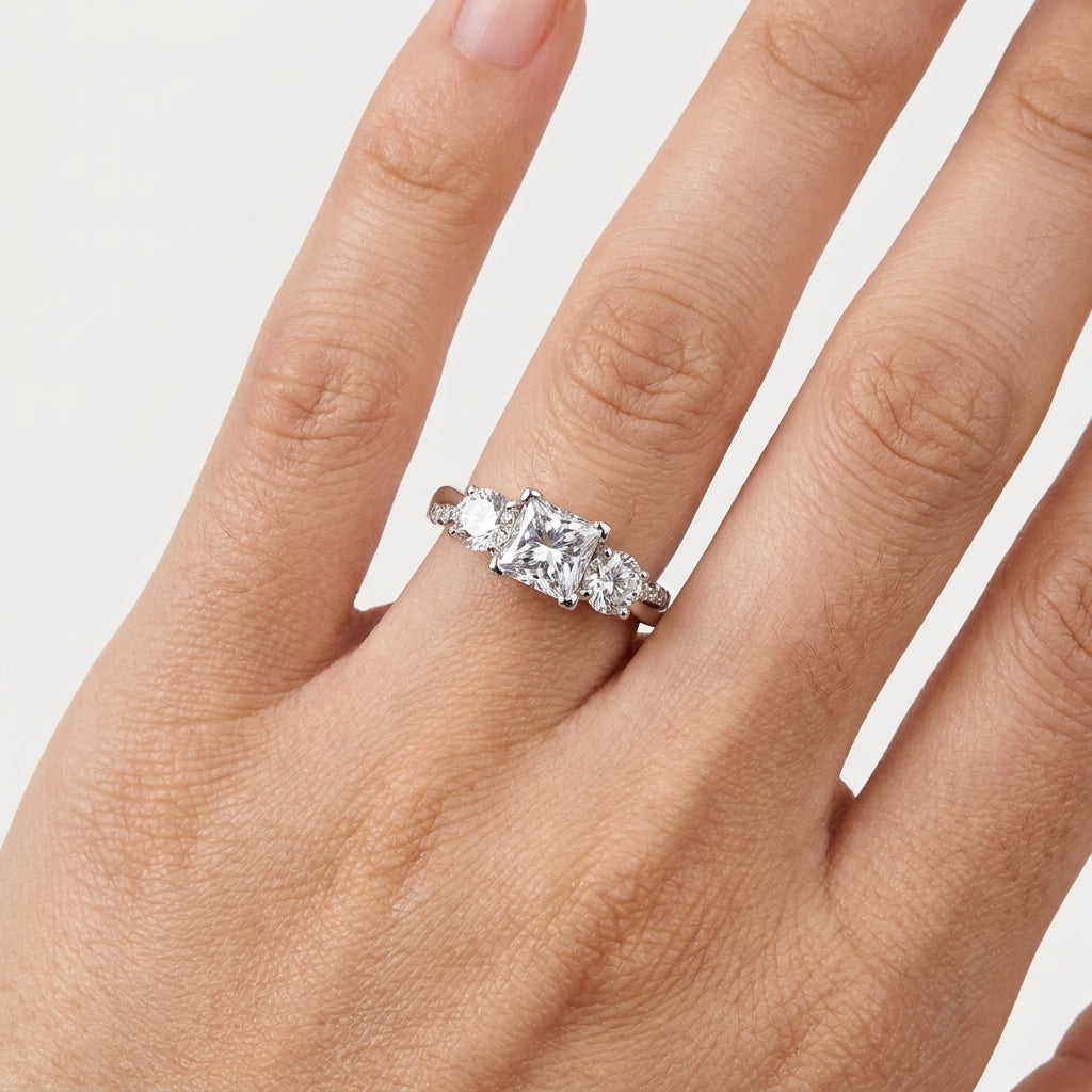 Close-up of a princess-cut moissanite ring with two round side stones