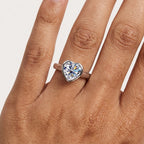 Close-up of a heart-cut moissanite bezel engagement ring worn on the hand