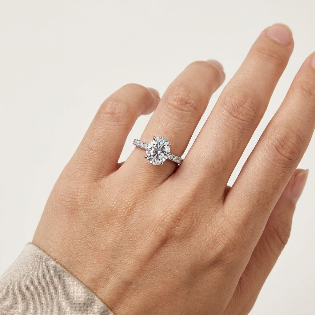 Close-up of an oval-cut moissanite solitaire ring with a sparkling pavé band