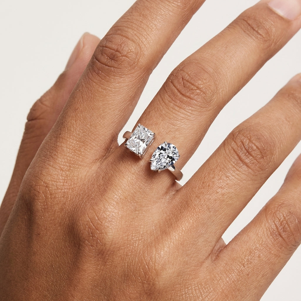 Close-up of a radiant and pear-cut moissanite Toi et Moi ring worn on the hand