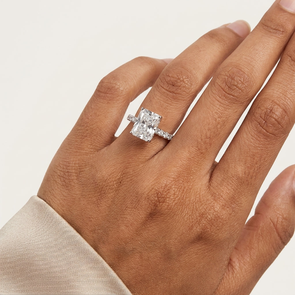 Close-up of a radiant-cut moissanite ring with pavé band worn on the hand