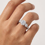 Close-up of a three-stone round-cut moissanite engagement ring worn on the hand.