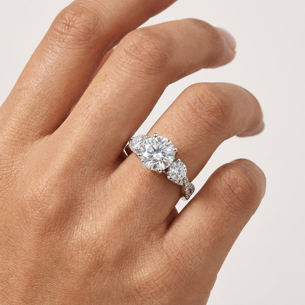 Close-up of a three-stone round-cut moissanite engagement ring worn on the hand.