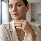 Woman wearing a round-cut moissanite bridal ring set with a cream blouse.